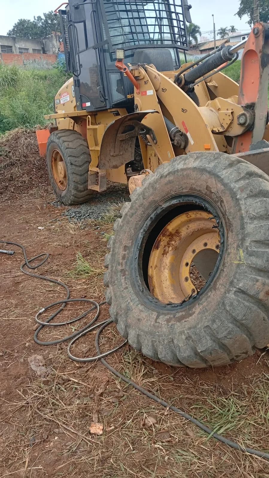 pá carregadeira amarela numa obra, com o pneu gigante fora do aro
