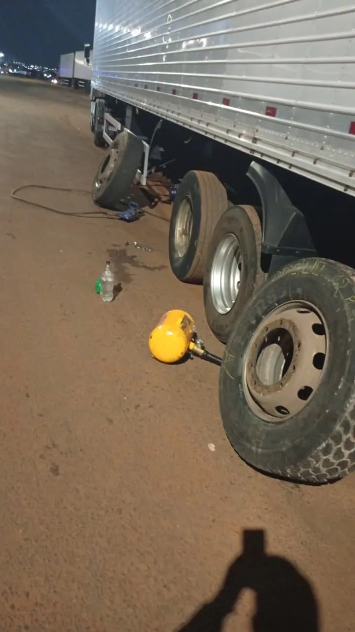 carreta frigorífica num pátio à noite, com uma roda tirada no chão e o macaco ao lado